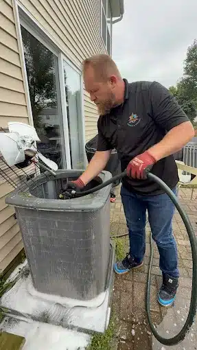 HVAC technician performing maintenance and repair of an outdoor residential air conditioning unit in Lake in the Hills, IL (McHenry County)